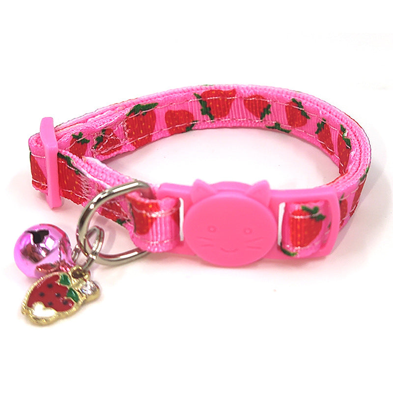 Pink dog collar with strawberry pattern and bell charm on a white background