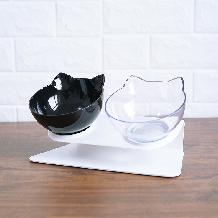 Two cat-shaped bowls on a white stand with a white tiled wall background