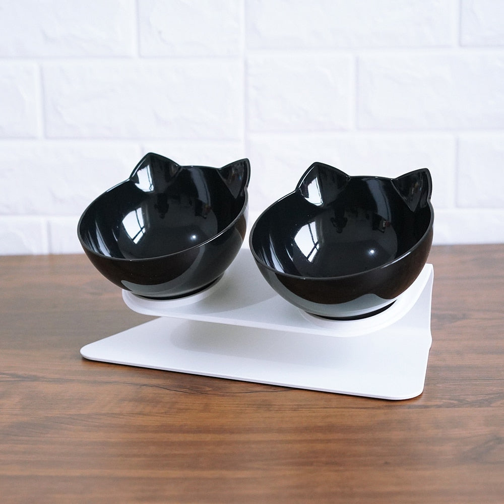 Black cat-shaped bowls on a white stand against a white brick wall.
