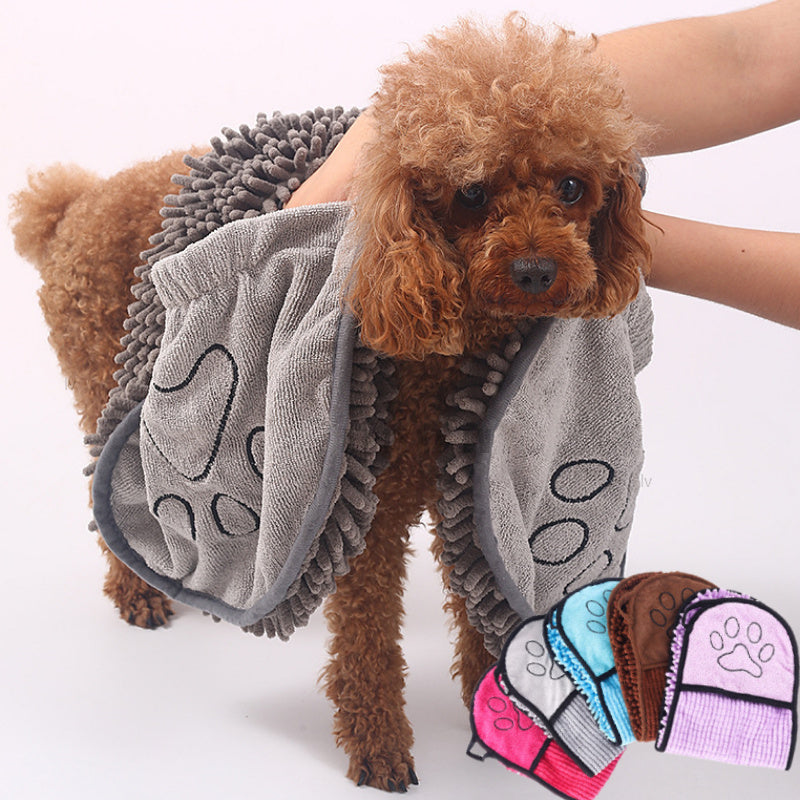 Dog wearing a gray towel with paw prints, surrounded by additional towels in different colors on a white background.