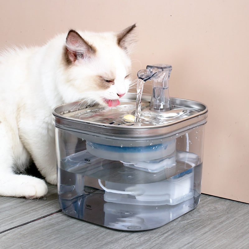 Cat drinking water from a pet fountain on a wooden floor.