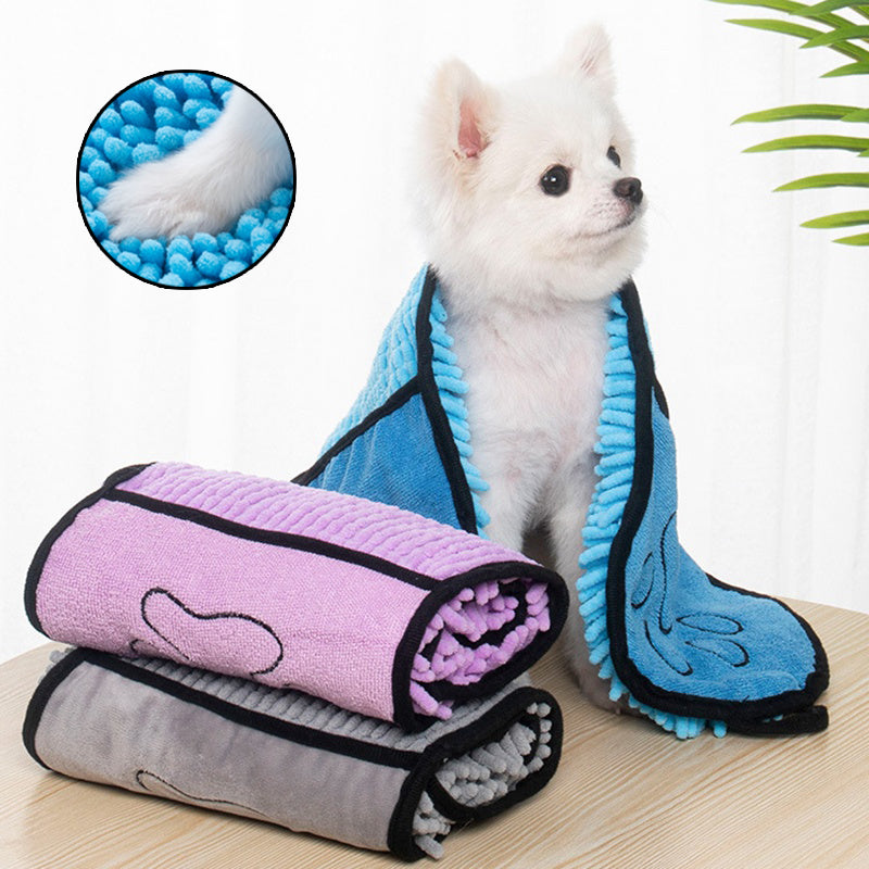 White dog with rolled-up pet towels on a wooden surface